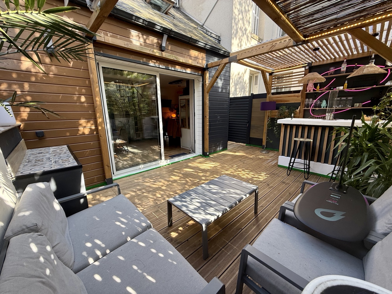 Terrasse en bois aménagée avec une pergola et un bar